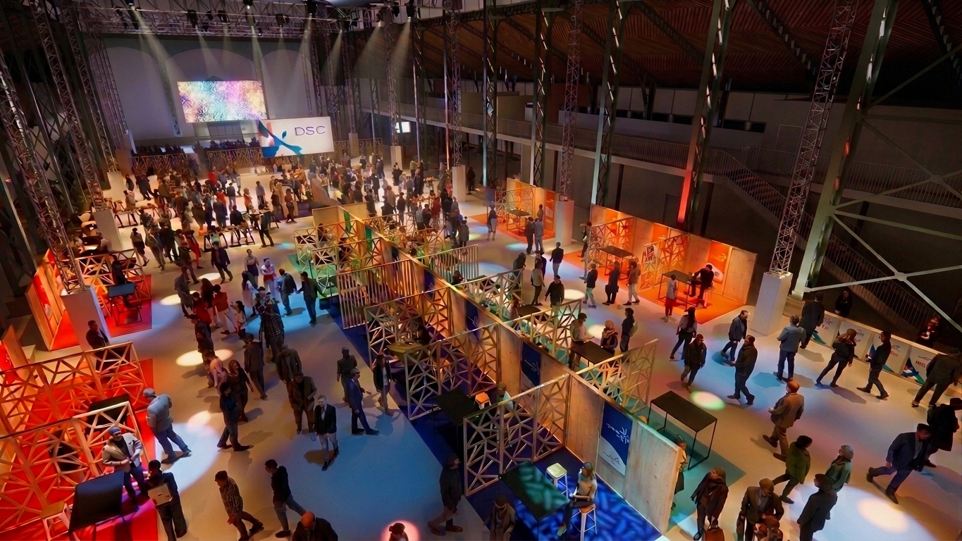 La halle baignée de reflets chauds et bleutés, le public circulant entre les rangées de stands